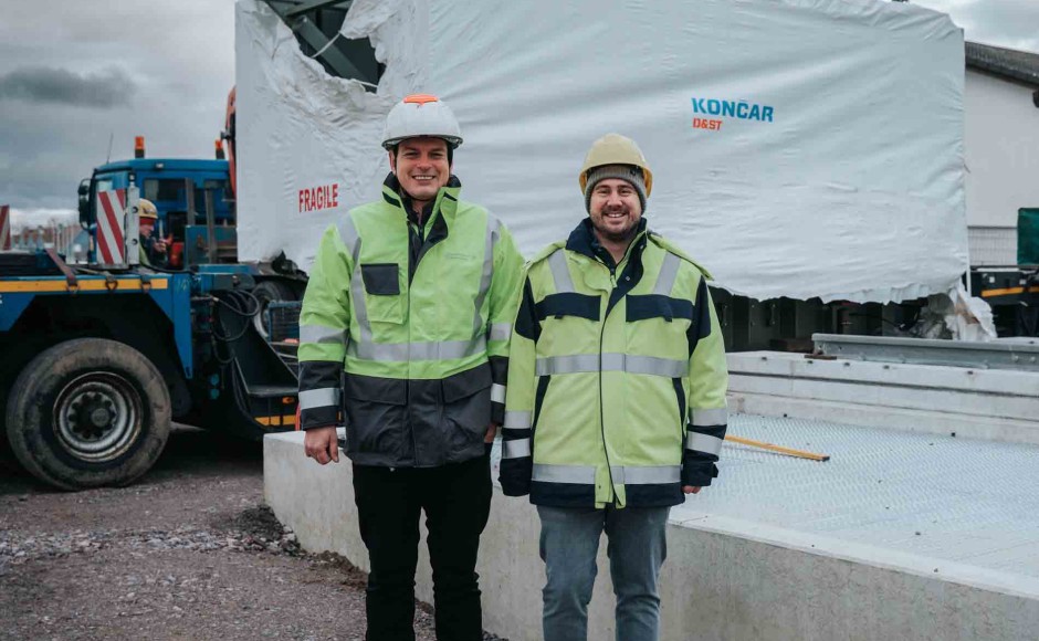 Matthias Böhmann, Technischer Geschäftsführer Überlandwerk Mittelbaden, und Dominik Ramm, Projektleiter Überlandwerk Mittelbaden, vor dem frisch angelieferten und noch verpackten Transformator in Rheinau-Freistett
