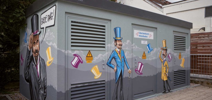 Auf dem Schulhof der Realschule in der Hauptstraße 14a steht die zweite neu gestaltete Trafostation mit dem Motiv des Klappzylinders. Die Stadt Achern erinnert hiermit an den weltweiten Exportschlager, den „Chapeau Claque“.